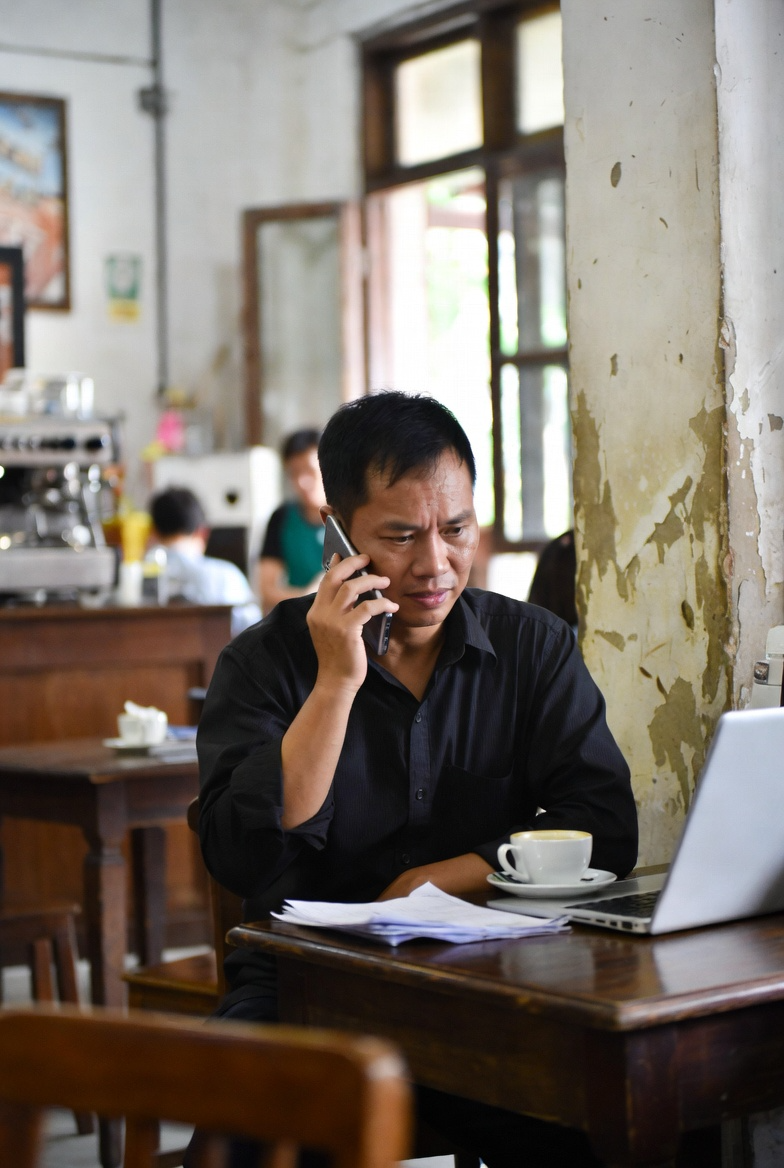 Một người đàn ông Việt Nam trung niên ngồi trong quán cà phê